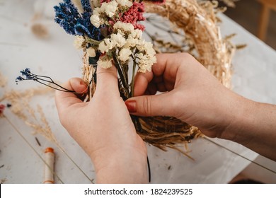 Girl making floral door wreath using colorful dry summer flowers and plants.  Fall flower decoration workshop