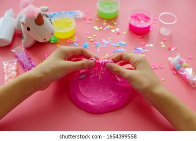 A Girl Making Slime Herself. Child Making Slime On Pink Background.