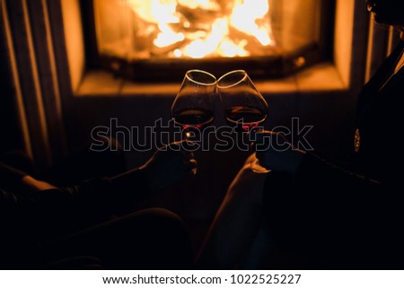 girl and  man at the fireplace drink wine