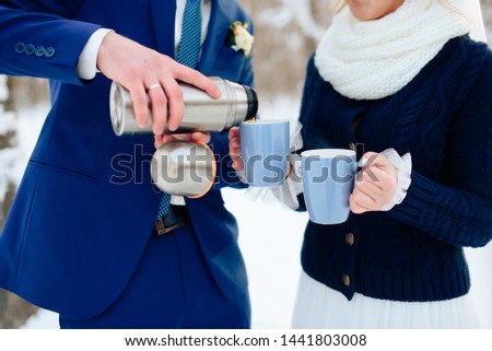 girl with a man on the nature in winter hold cups of hot drink