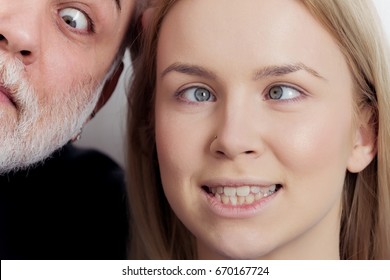 Girl and man squinting eyes on silly faces. Young woman with crossed grey eyes and makeup foundation and old male with white beard. Grimace. Strabismus
