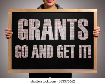 Girl (manager, student, businesswoman) in casual clothes holding a black chalk board with the text Grants go and get it - Powered by Shutterstock