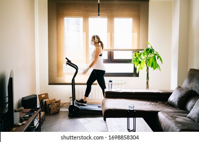 A Girl With Mask And Gloves Slim Athlete Does Exercise At Home Running On The Treadmill. Confinement Virus Pandemic Training Concept