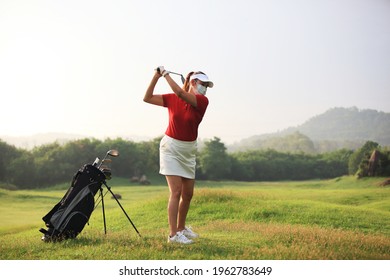 girl with mask on face for protect  corona virus and she is playing  golf on course. Golfer with golf club taking a shot - Powered by Shutterstock