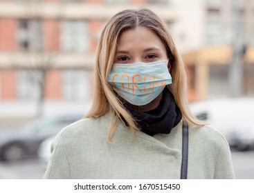 Mädchen mit Maske, um sie vor dem Corona-Virus zu schützen. Corona auf Maske geschrieben. Frau mit Maske, die vor einem Klinikgebäude steht. Schönes blondes Mädchen mit medizinischer Maske. Corona-Virus-Pandemie
