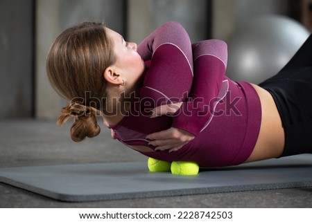 A girl massages the trigger point of her back with balls. The concept of myofascial release, self-massage.