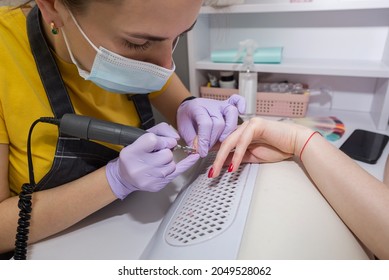 Girl Master Makes A Manicure To A Client Using A Milling Machine In A Nail Salon.