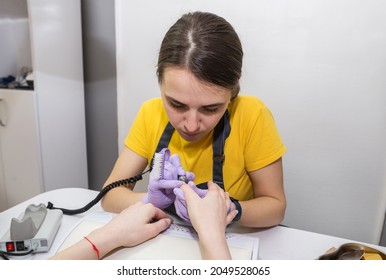 Girl Master Makes A Manicure To A Client Using A Milling Machine In A Nail Salon.