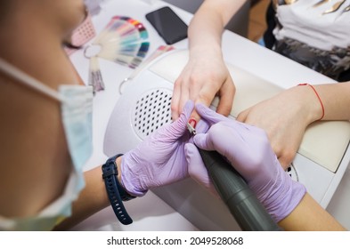 Girl Master Makes A Manicure To A Client Using A Milling Machine In A Nail Salon.