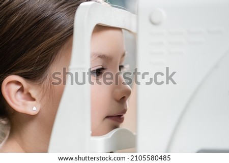 girl measuring eyesight on blurred ophthalmoscope