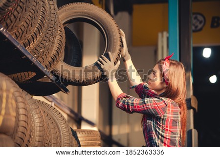Girl mechanic at repair shop changing tires