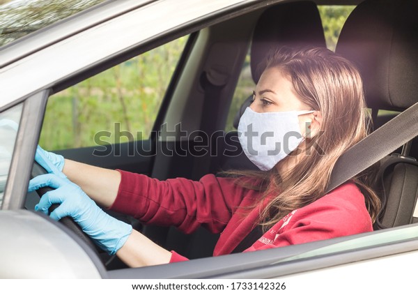 girl in medical\
mask and gloves driving a car. personal protective equipment during\
the period of coronavirus, epidemic. young woman takes care of her\
health while traveling