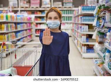 Girl In Medical Mask Reaches Hand And Shows Stop Sign Shopping In Supermarket During Outbreak Coronavirus Pneumonia Makes Panic Stock Products. Empty Store Shelves Set Things Quarantine Self-isolation