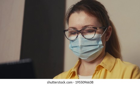 girl in a medical protective mask works at home Office a laptop in the office. Stay home social distance coronavirus concept. Woman in medical protective mask working home. social distance - Shutterstock ID 1955096638