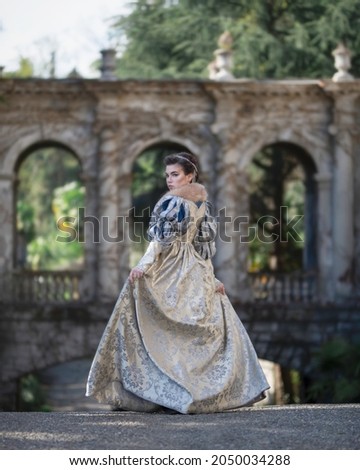 Girl in medieval dress against the background of ancient arches