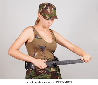 The girl in military clothes, buttons bandolier of bullets. Gray background. - Powered by Shutterstock