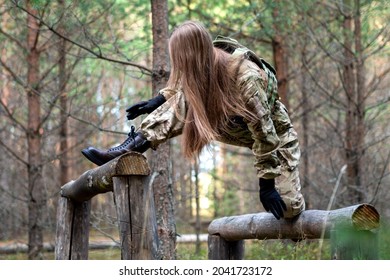 A Girl In Military Equipment Passes An Obstacle Course In A Forest Camp At An Army Training Ground.