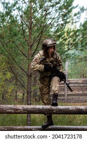 A Girl In Military Equipment Passes An Obstacle Course In A Forest Camp At An Army Training Ground.