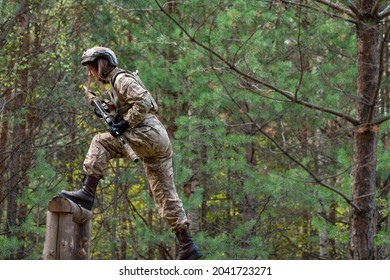 A Girl In Military Equipment Passes An Obstacle Course In A Forest Camp At An Army Training Ground.