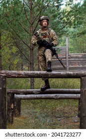 A Girl In Military Equipment Passes An Obstacle Course In A Forest Camp At An Army Training Ground.