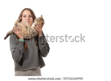 girl with mischievous expression holding cat close to her face, isolated white background
