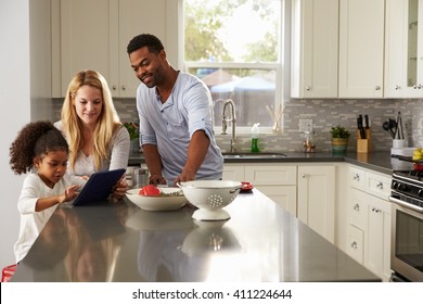 Girl and mixed race parents use tablet computer in kitchen
