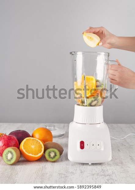 Girl mixing fruits\
with electric blender.