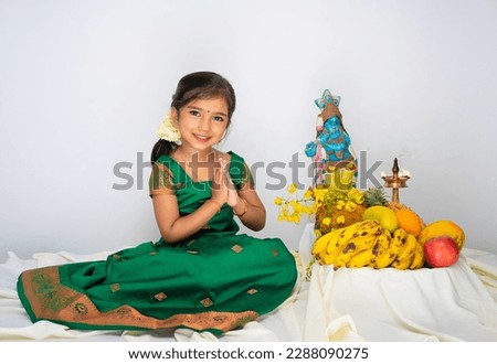 girl model in green skirt and blouse arranging vishu kani in white background for banner and cut out