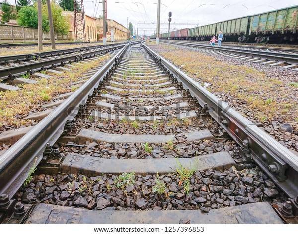 The\
girl and the mother cross railway tracks. Cars of a freight train.\
Rails and sleepers near the railway station.\
Danger.