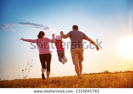 girl with mother and father holding hands on the nature. Child with parents outdoors