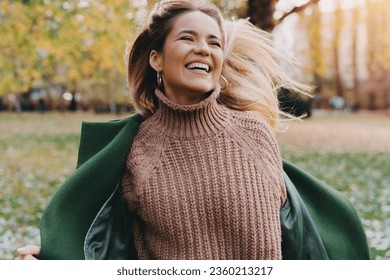 Girl in motion expressing happiness at city park. Attractive, cheerful woman running, feeling free and joyful during the nice autumn day. - Powered by Shutterstock