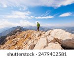girl in the mountains. a climber walks along a rocky ridge. girl climbs the mountains. mountaineering and rock climbing. concept of adventure and hiking in the mountains.