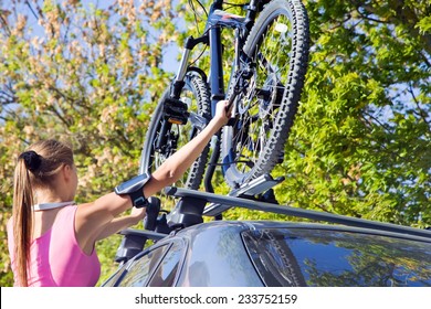 Girl mounted  transportation bikes on the roof of a car on a sunny day