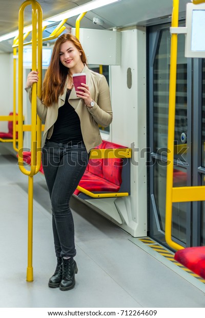 The girl with mug of coffee\
inside an empty subway train. Girl is in a metro car with mug of\
coffee