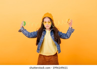 A girl in multi-colored shirt holds a multi-colored slinky toy in her hands