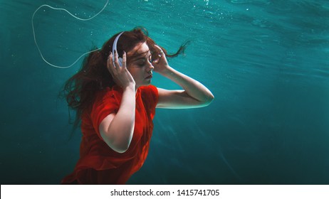 Girl Music Fan Enjoys The Music, The Concept. Deep Dive. Young Brunette Woman With Headphones On Her Head And Underwater