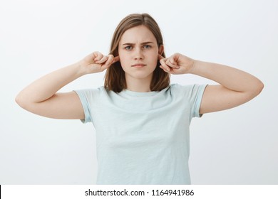 Girl Not Going Listen Shutting Up Ears. Intense Serious-looking Bothered Woman Covering Hearing With Index Fingers And Standing Indifferent And Uninvolved At Camera Unwilling Continue Conversation