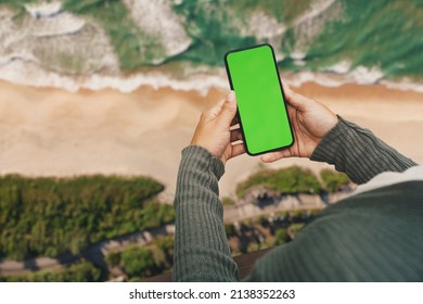 Girl on balcony of high floor apartment holding smartphone with Green screen. Beach in the background.Chroma Key. - Powered by Shutterstock