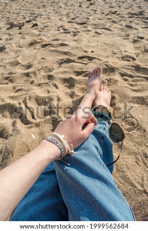 Girl on the beach in jeans holds sunglasses in her hand