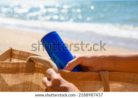 A girl on the beach takes out a can of cold drink from her bag. beach holiday concept