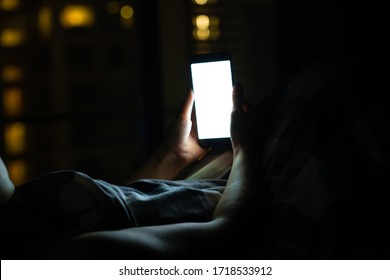 Girl on the bed before falling asleep looks at a smartphone. Check news and social networks before going to bed. Smart gadget. - Powered by Shutterstock