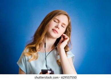 Girl on a blue background with headphones listening to music - Shutterstock ID 629557550