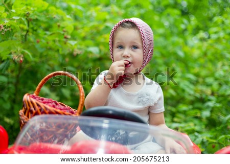 girl on the car and with a raspberry in nature