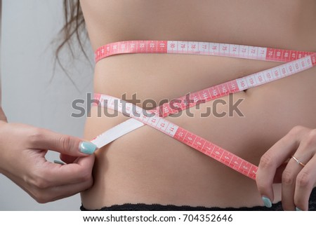 The girl on the diet measures her waist.