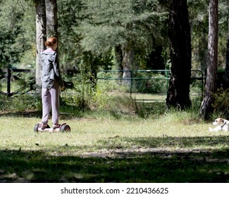 A Girl On A Hoverboard With A Dog Playing Outside