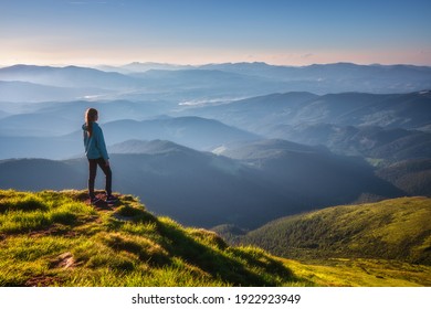 Mädchen auf dem Berggipfel mit grünem Gras Blick auf das schöne Bergtal im Nebel bei Sonnenuntergang im Sommer. Landschaft mit sportlicher junger Frau, nebligen Hügeln, Wald, Himmel. Reisen und Tourismus. Wandern