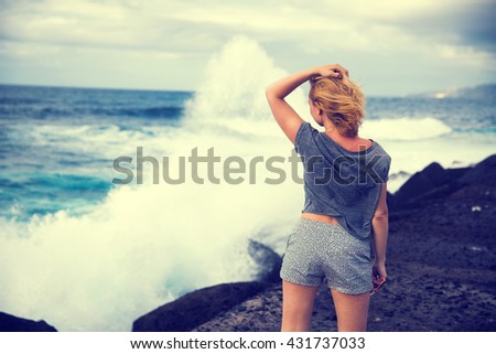 girl on the ocean watching the big waves