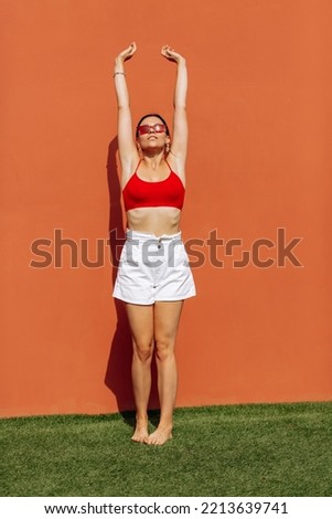 Girl on an orange background in red glasses. Cheerful girl, advertising shooting. High quality photo