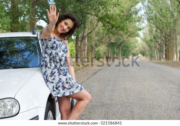 girl on road\
greeting gesture near white\
car