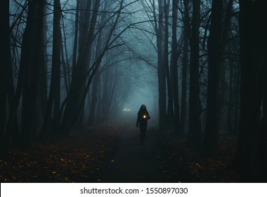 Girl on the road in a mysterious forest. Background wallpaper. Strange forest. Mystic atmosphere. Dark scary road. Paranormal another world. Ghost in the fog. The pursuit. Horrible dream.
